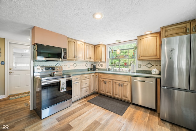 kitchen featuring light hardwood / wood-style flooring, stainless steel appliances, backsplash, and a textured ceiling