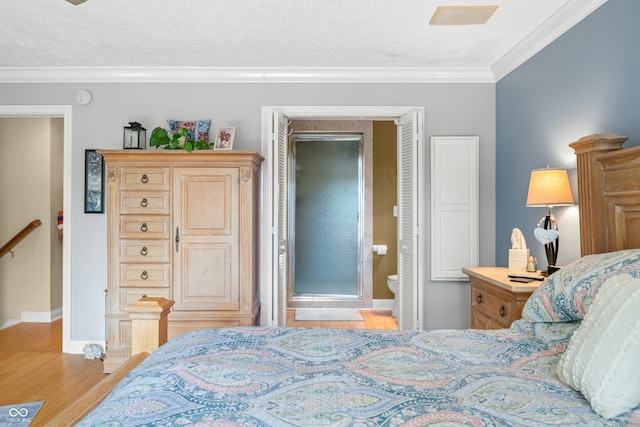 bedroom with a textured ceiling, crown molding, light hardwood / wood-style floors, and ensuite bathroom