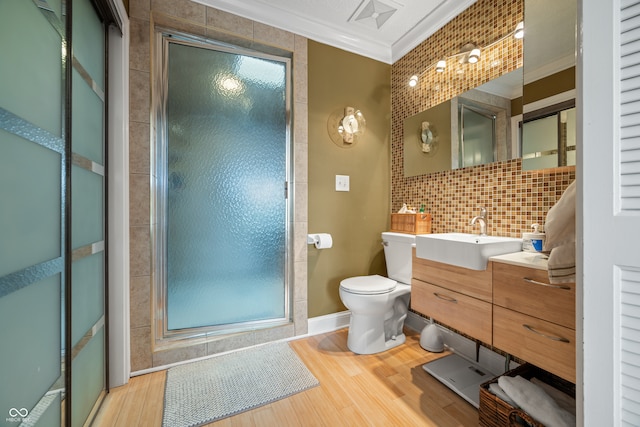 bathroom with a shower with shower door, crown molding, hardwood / wood-style floors, vanity, and toilet