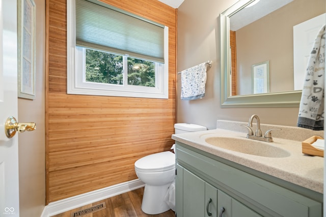 bathroom featuring wood-type flooring, vanity, wood walls, and toilet