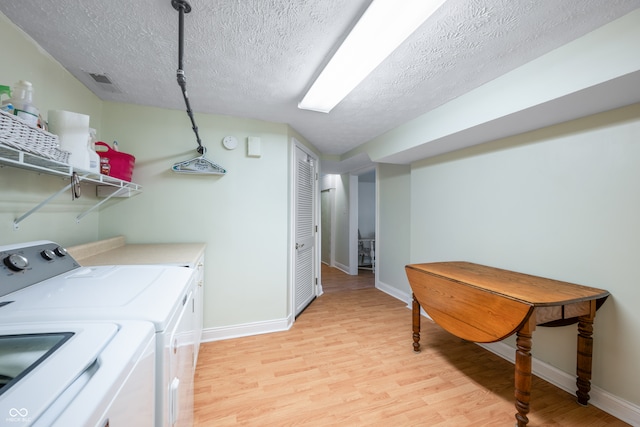 laundry room with a textured ceiling, light hardwood / wood-style floors, and washing machine and dryer