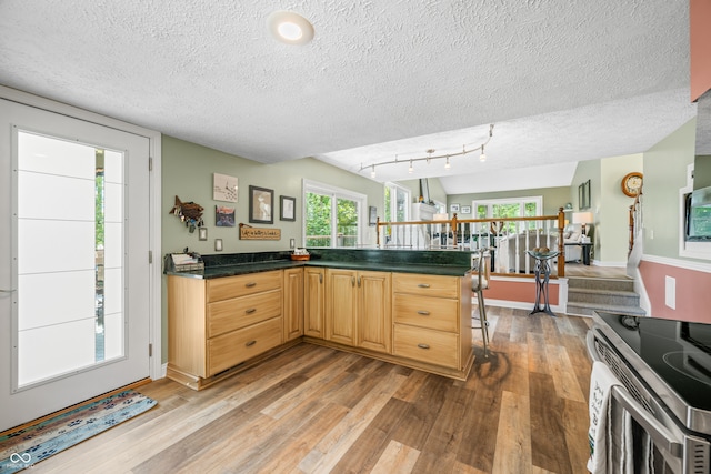 kitchen with a breakfast bar area, a textured ceiling, and light hardwood / wood-style flooring