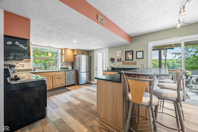 kitchen featuring a textured ceiling, light wood-type flooring, plenty of natural light, and black appliances