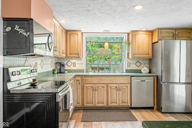 kitchen featuring pendant lighting, light hardwood / wood-style floors, sink, stainless steel appliances, and backsplash