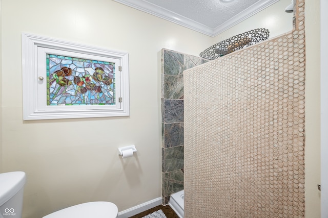 bathroom with tiled shower, a textured ceiling, crown molding, and toilet