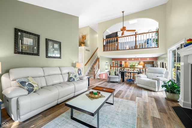 living room featuring a towering ceiling, ceiling fan, and hardwood / wood-style flooring