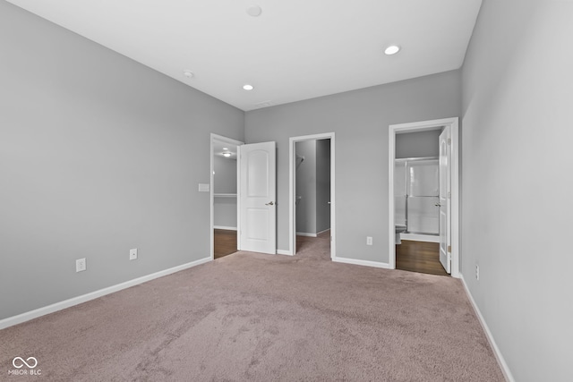 unfurnished bedroom featuring dark carpet, a spacious closet, connected bathroom, and a closet