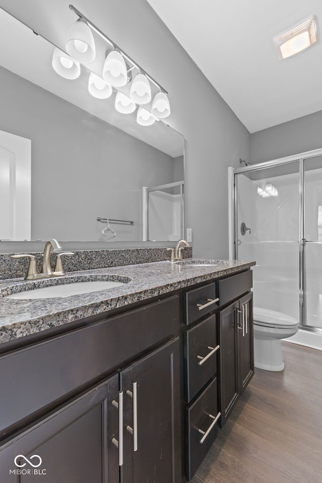 bathroom with a shower with shower door, toilet, wood-type flooring, and vanity