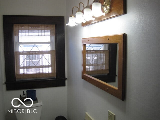 bathroom featuring a wealth of natural light, toilet, and an inviting chandelier