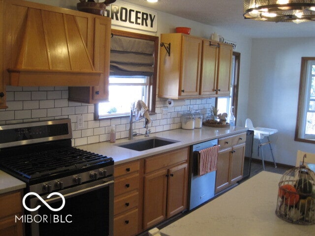 kitchen featuring custom range hood, decorative backsplash, appliances with stainless steel finishes, and sink