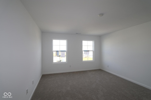 unfurnished room with dark colored carpet