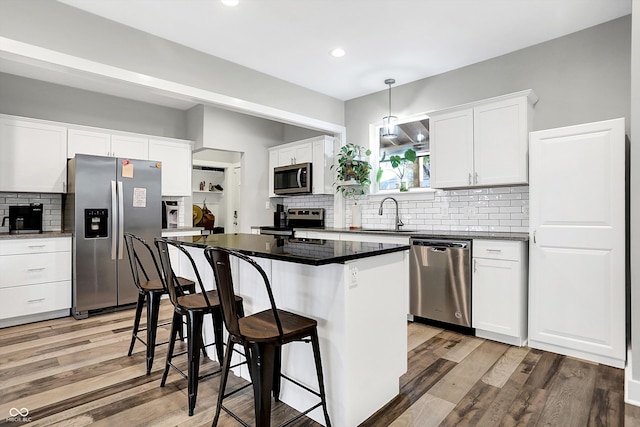 kitchen featuring a center island, sink, light hardwood / wood-style floors, white cabinetry, and stainless steel appliances