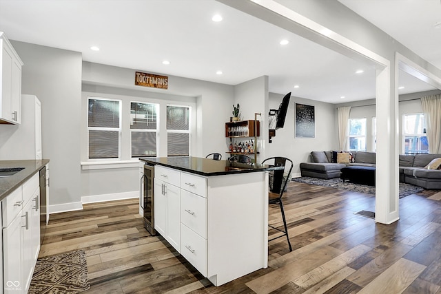 kitchen with a center island, wood-type flooring, white cabinetry, and wine cooler