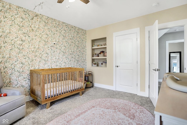 bedroom with a crib, carpet, and ceiling fan