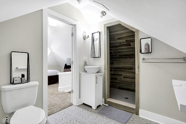 bathroom with vanity, toilet, a tile shower, and vaulted ceiling