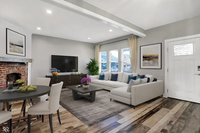 living room with hardwood / wood-style floors, beamed ceiling, and a brick fireplace