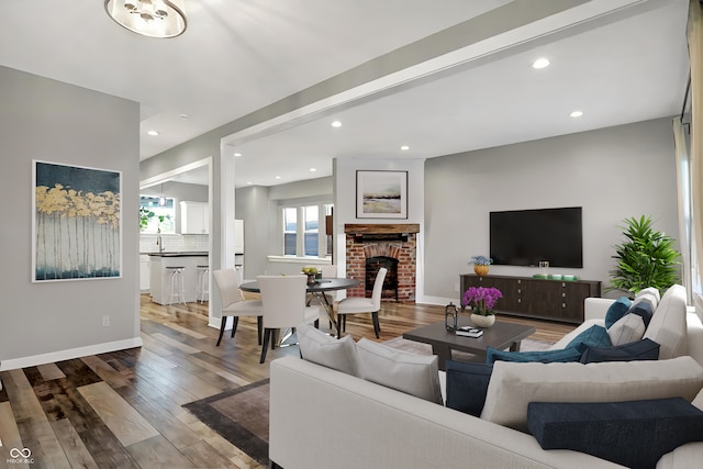 living room with sink, hardwood / wood-style floors, and a brick fireplace