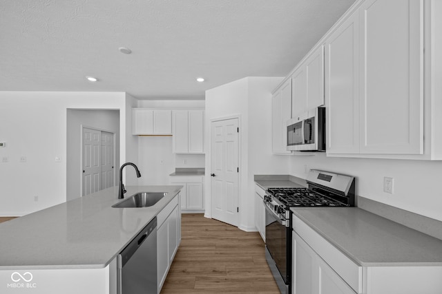 kitchen featuring sink, a kitchen island with sink, white cabinetry, stainless steel appliances, and light hardwood / wood-style floors