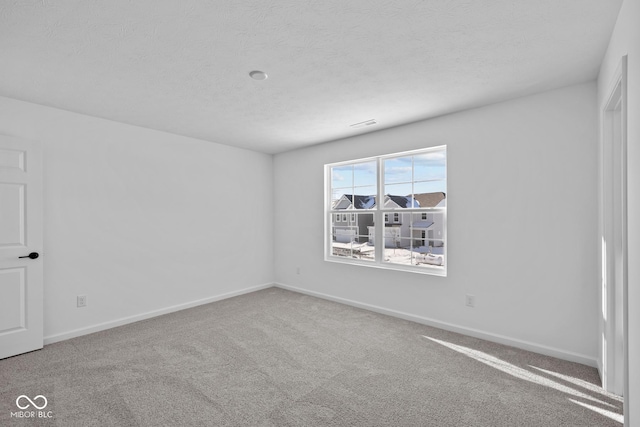 carpeted empty room with a textured ceiling