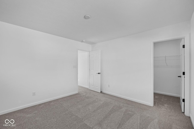 unfurnished bedroom with a walk in closet, light colored carpet, and a closet