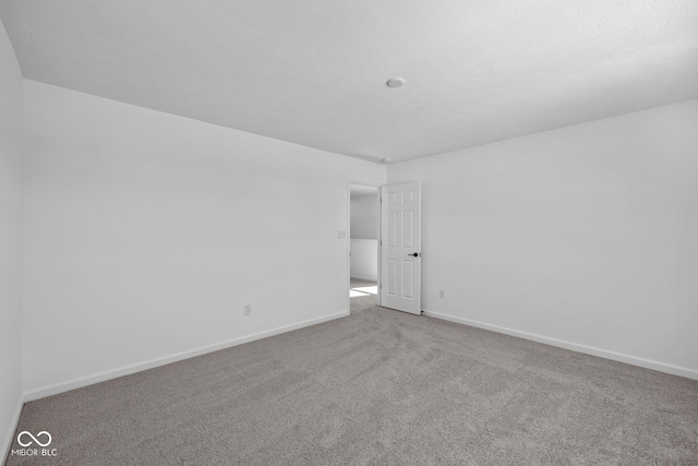 spare room featuring light colored carpet and a textured ceiling