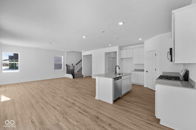 kitchen featuring sink, dishwasher, light hardwood / wood-style floors, an island with sink, and white cabinets