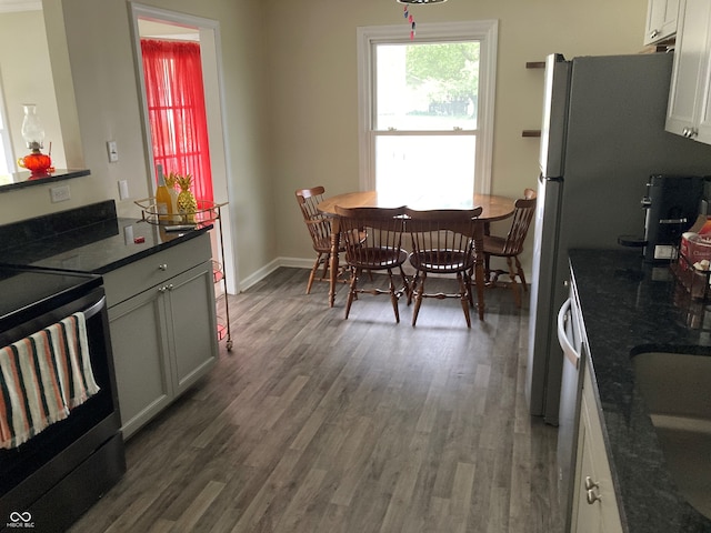 kitchen with dark stone countertops, white cabinetry, stainless steel electric stove, and dark hardwood / wood-style floors