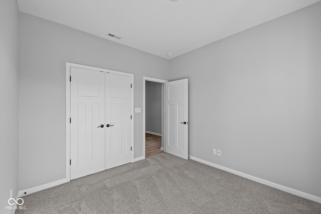 unfurnished bedroom with light carpet and a closet