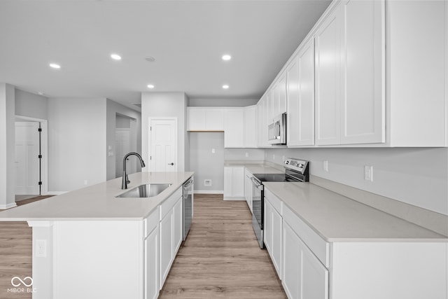 kitchen with sink, light hardwood / wood-style flooring, an island with sink, white cabinetry, and stainless steel appliances