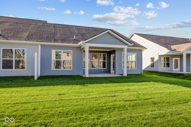 back of house with a patio and a lawn