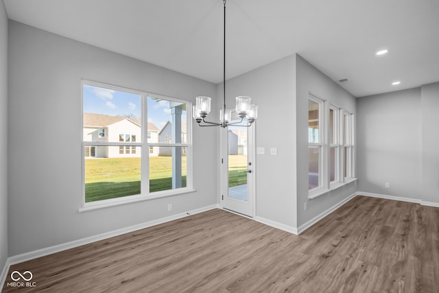 unfurnished dining area with hardwood / wood-style floors and an inviting chandelier