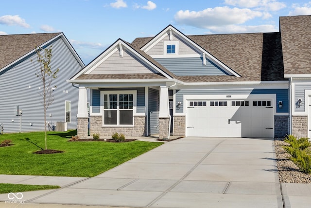 craftsman-style home featuring central air condition unit, a front yard, and a garage