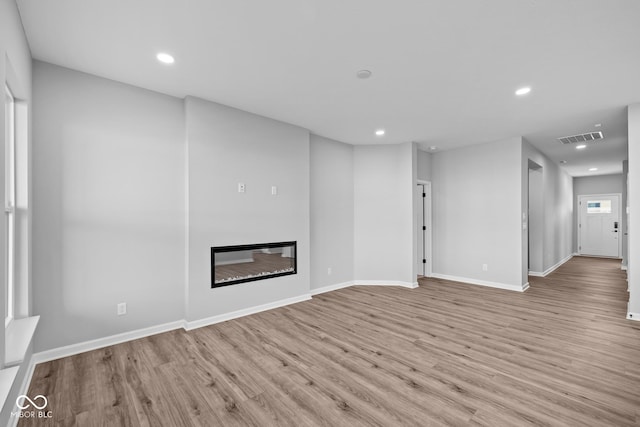10618 Maidenhair Dr, Indianapolis, IN 46239 - unfurnished living room with recessed lighting, light wood finished floors, baseboards, and a glass covered fireplace