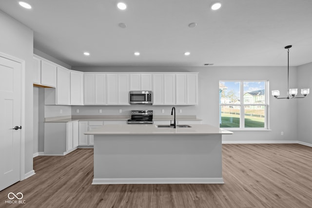 kitchen featuring white cabinets, a center island with sink, sink, light hardwood / wood-style flooring, and stainless steel appliances