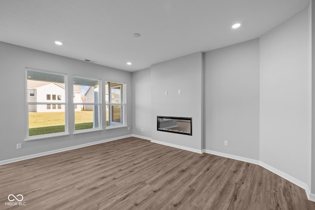 10618 Maidenhair Dr, Indianapolis, IN 46239 - unfurnished living room featuring wood finished floors, baseboards, recessed lighting, and a glass covered fireplace