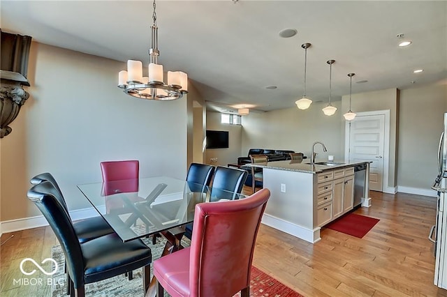 dining space featuring light hardwood / wood-style flooring, a chandelier, and sink