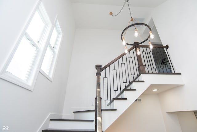 stairs featuring a towering ceiling and a chandelier