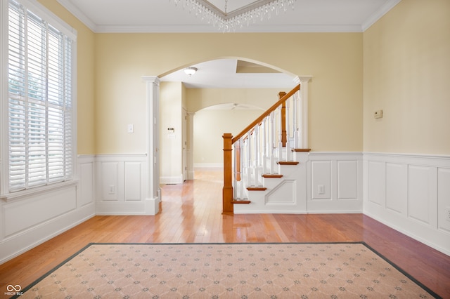 entryway with an inviting chandelier, crown molding, and light hardwood / wood-style floors