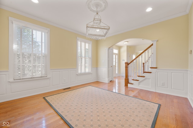 foyer entrance with ornamental molding, a notable chandelier, hardwood / wood-style floors, and a healthy amount of sunlight