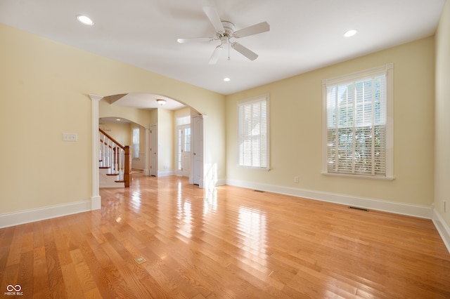 empty room featuring ornate columns, ceiling fan, and light hardwood / wood-style floors