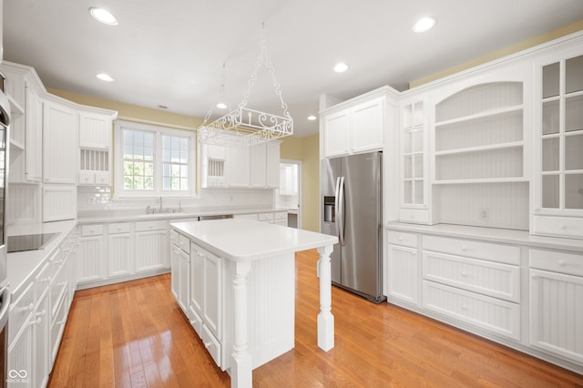 kitchen with stainless steel fridge, a kitchen island, white cabinets, and light hardwood / wood-style flooring