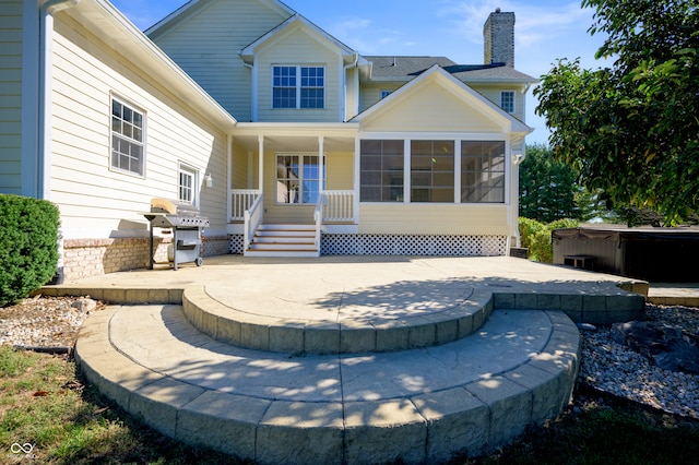 back of house featuring a sunroom, a patio, and a hot tub