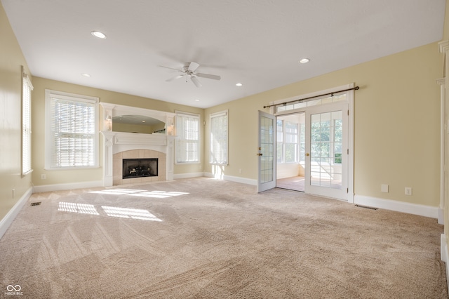 unfurnished living room with light carpet, ceiling fan, and a tile fireplace