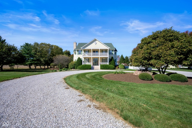 greek revival inspired property with a front yard, a balcony, and covered porch