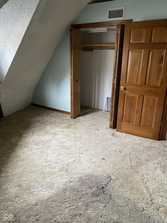 bonus room with vaulted ceiling and light carpet