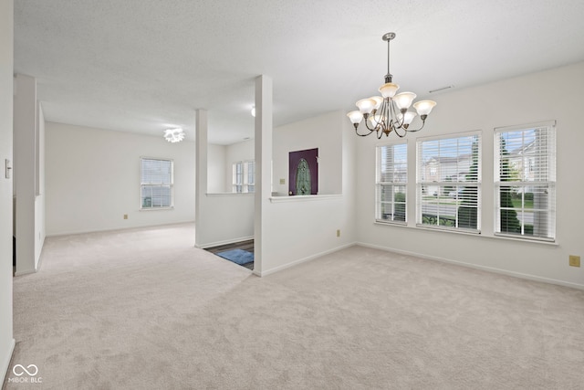 carpeted empty room with a textured ceiling and an inviting chandelier