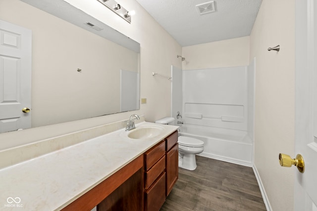 full bathroom featuring vanity, bathtub / shower combination, a textured ceiling, hardwood / wood-style flooring, and toilet