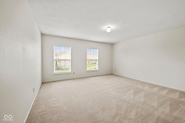 spare room featuring a textured ceiling and light carpet