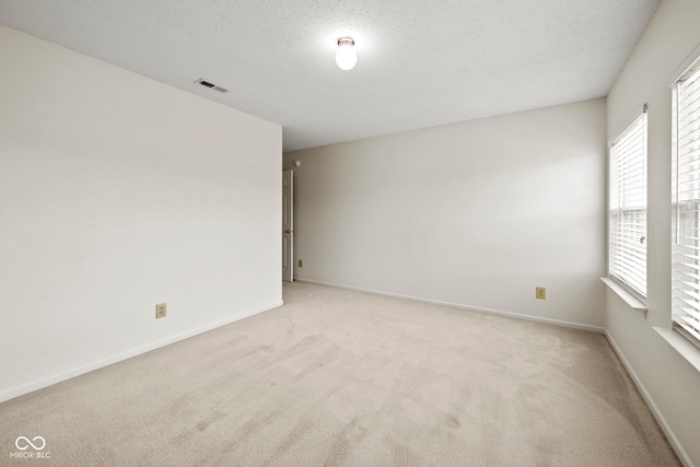 carpeted empty room featuring a textured ceiling