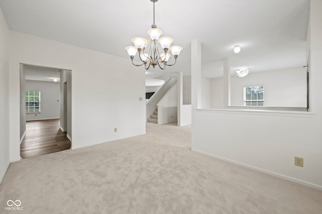 carpeted empty room featuring a notable chandelier